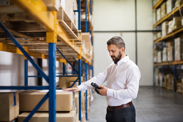 Warehouse worker or supervisor with barcode scanner. A mobile handheld PC with barcode scanner.