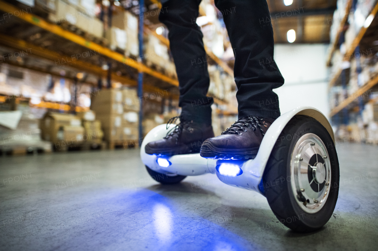 Unrecognizable man warehouse worker on a hoverboard.