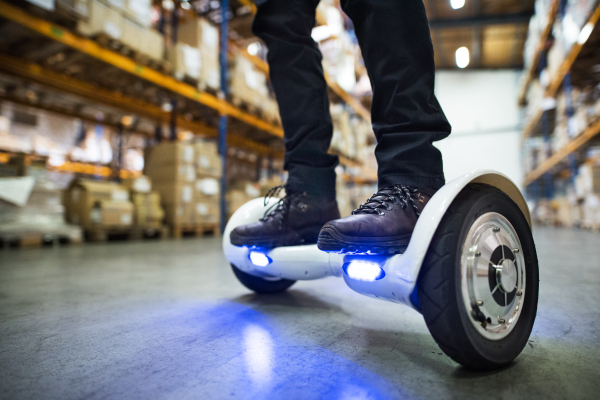 Unrecognizable man warehouse worker on a hoverboard.