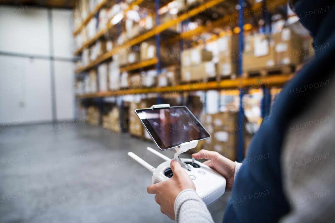 Unrecognizable man with tablet and drone controller standing in a warehouse.