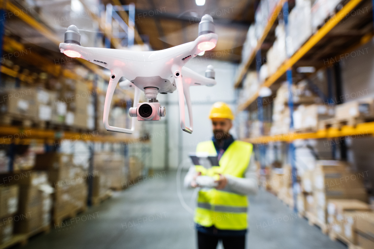 Man or a worker with drone standing in a warehouse.