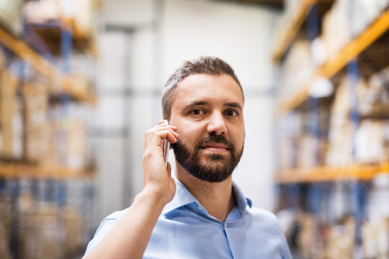 Warehouse worker or supervisor with a smartphone, making a phone call.