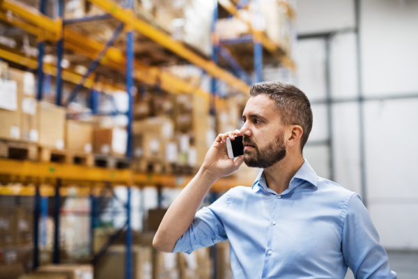 Warehouse worker or supervisor with a smartphone, making a phone call.