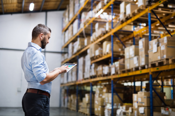 Handsome man warehouse worker with a tablet.