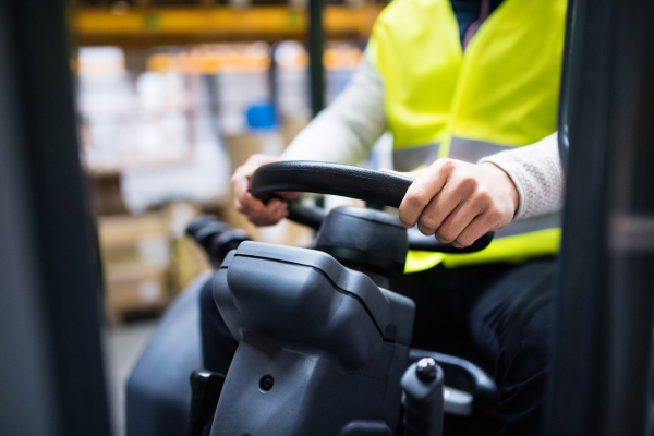 Unrecognizable man forklift driver working in a warehouse.