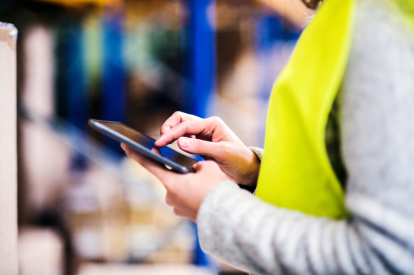 Unrecognizable young woman warehouse worker with tablet. A supervisor controlling stock.