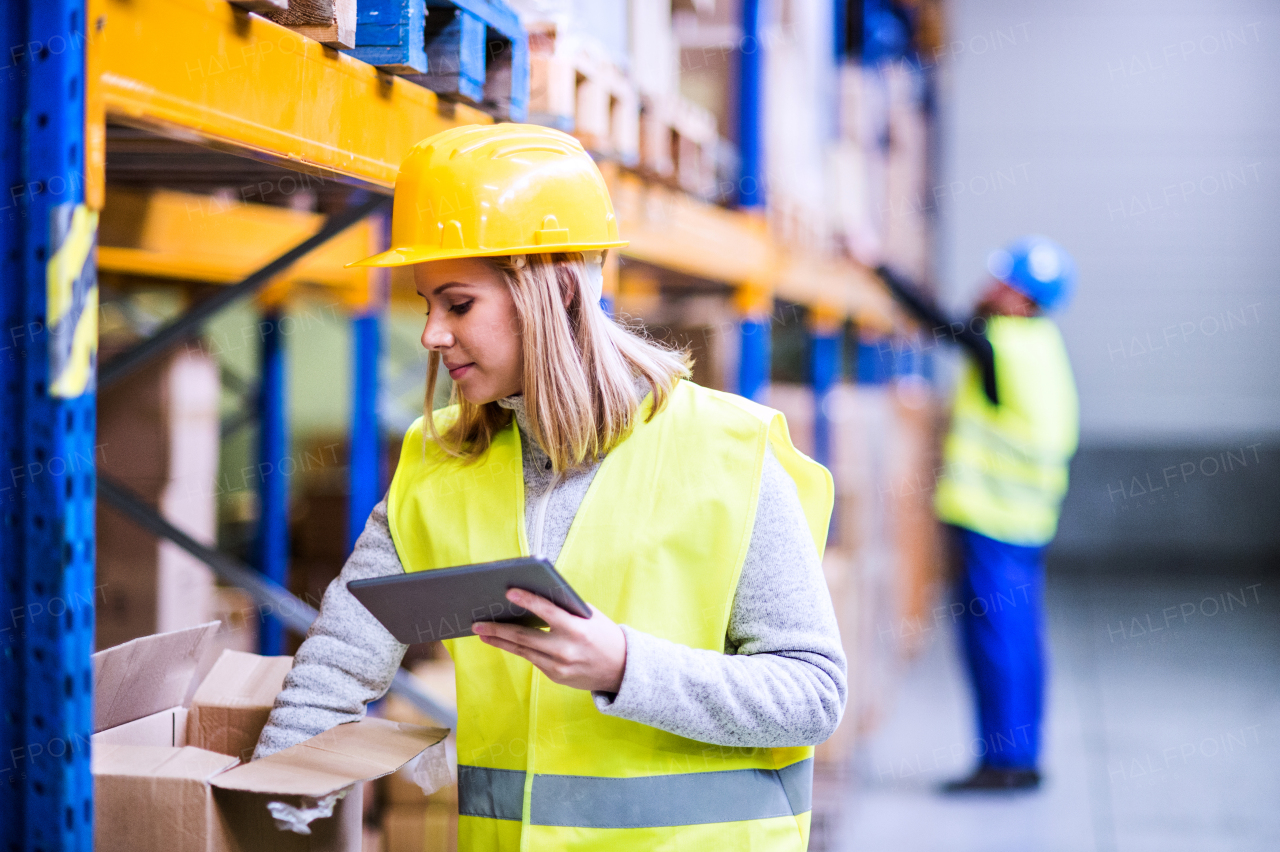 Young woman worker or supervisor with tablet. Warehouse workers controlling stock.