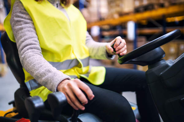 Unrecognizable young woman warehouse worker with forklift.