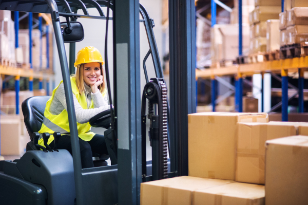 Beautiful young woman warehouse worker with forklift.