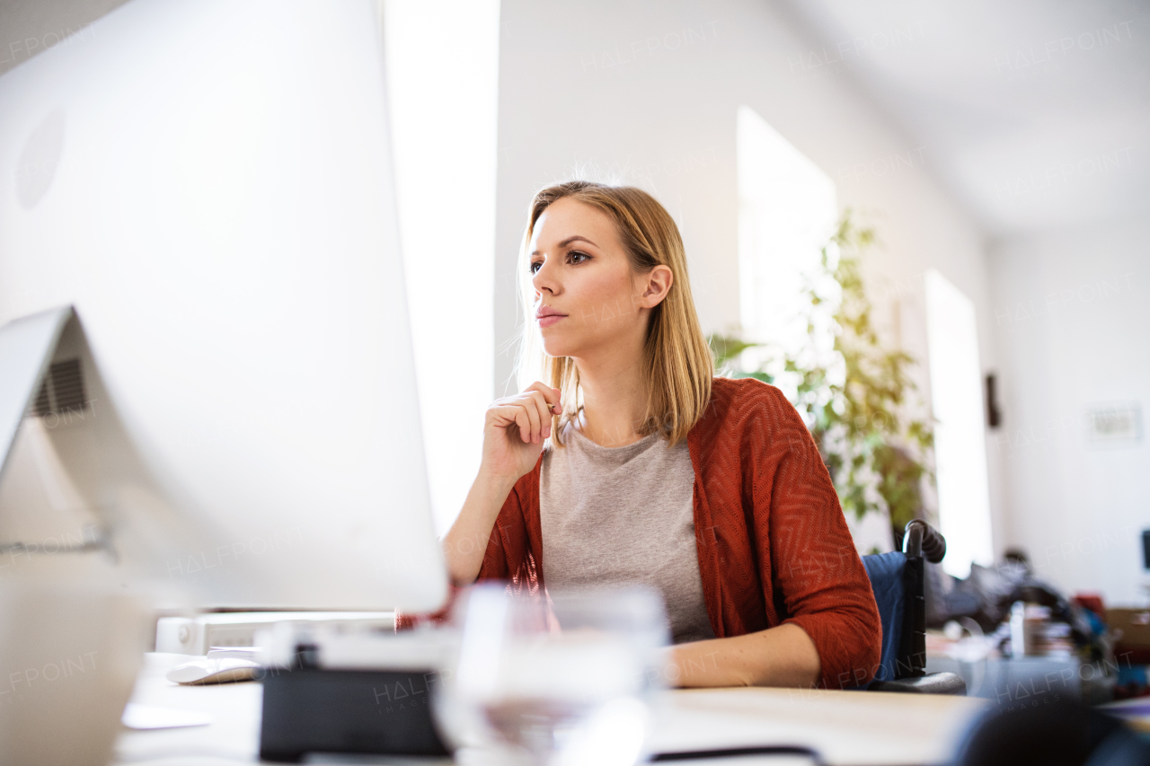 Businesswoman in wheelchair sitting at the desk, working.