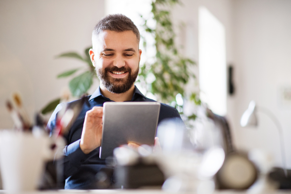 Handsome businessman with tablet at the desk in the office, working.