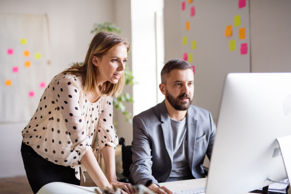 Two business people with wheelchair in the office working together.