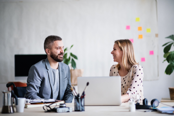 Two business people with wheelchair in the office working together.