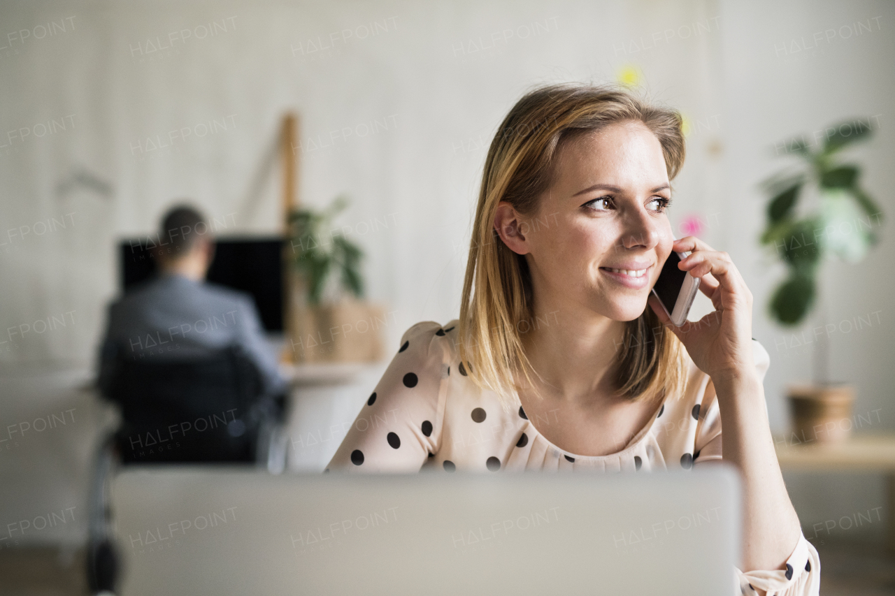 Two business people with wheelchair and smartphone working in the office.