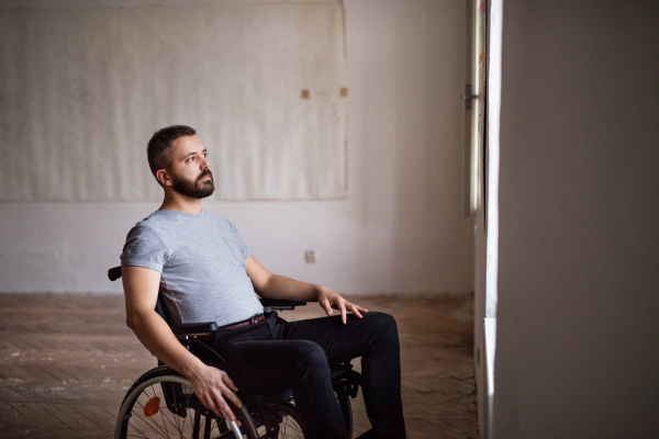 Hnadsome man in wheelchair looking out of the window.