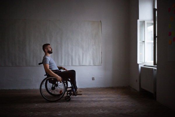 Hnadsome man in wheelchair looking out of the window.