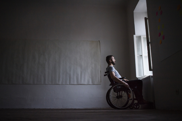 Hnadsome man in wheelchair looking out of the window.