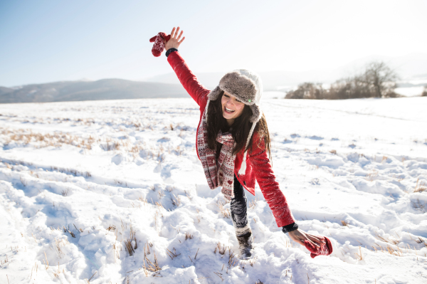 Beautiful young woman with her family, having fun in the snow. Sunny white winter nature.