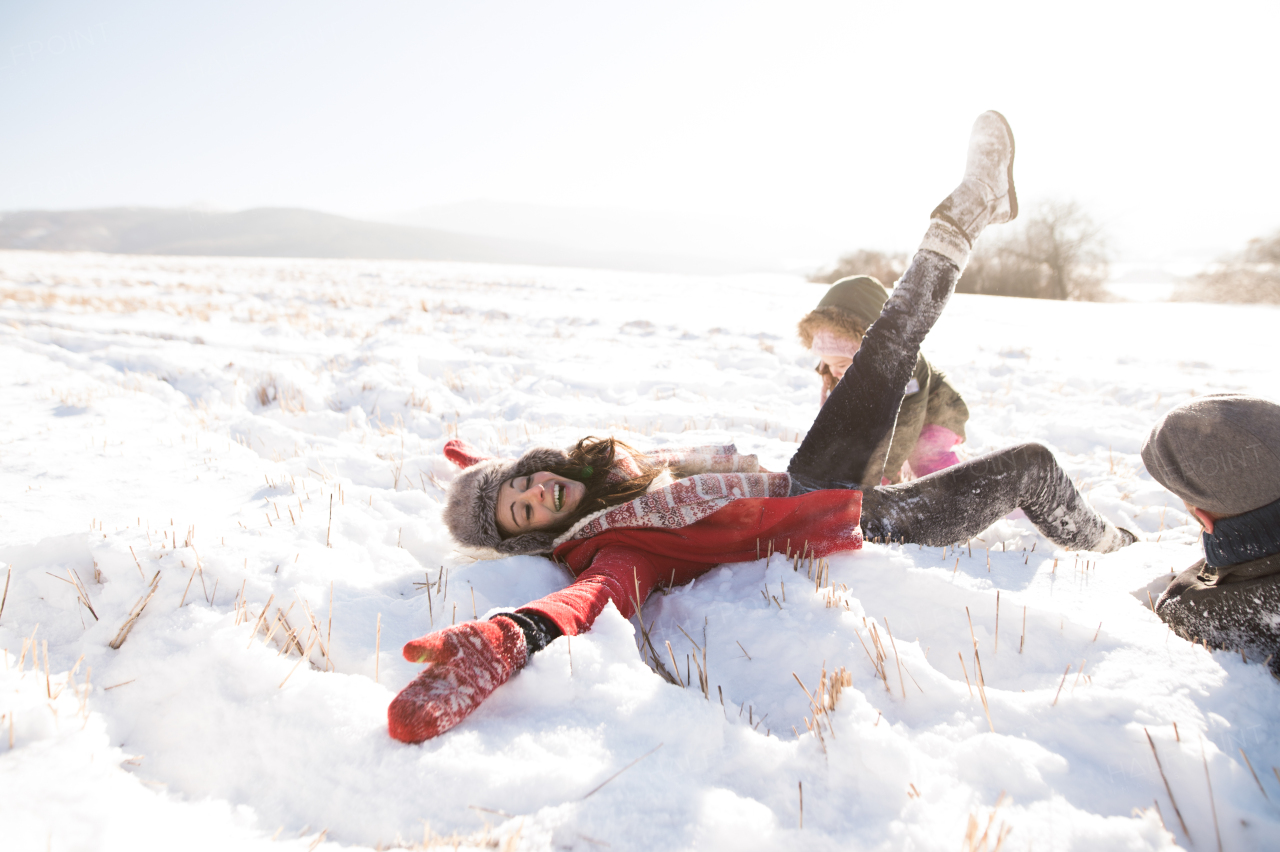 Father and mother having fun with their daughter, playing in the snow. Sunny white winter nature.