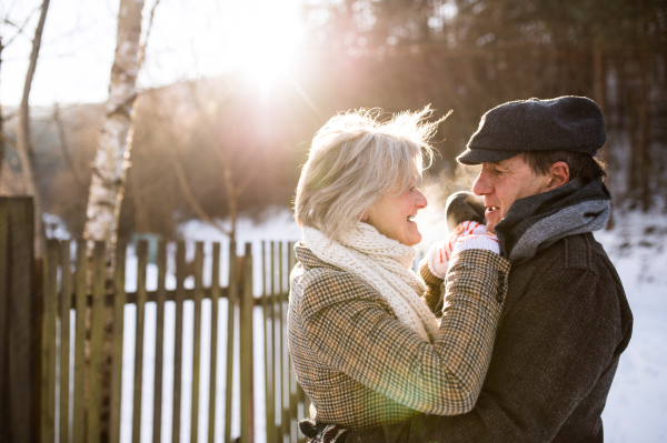 Beautiful senior woman and man on a walk in sunny winter nature, hugging