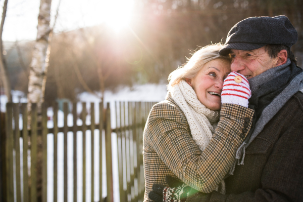 Beautiful senior woman and man on a walk in sunny winter nature, hugging