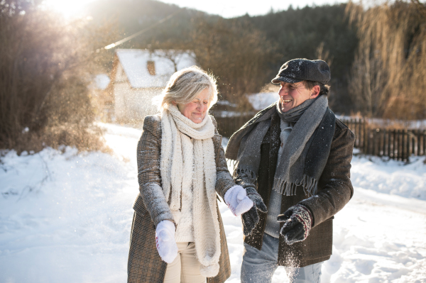 Beautiful senior woman and man on a walk in sunny winter nature, blowing snow.