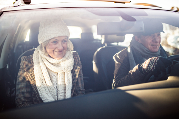 Beautiful senior woman and man in winter clothes driving a car