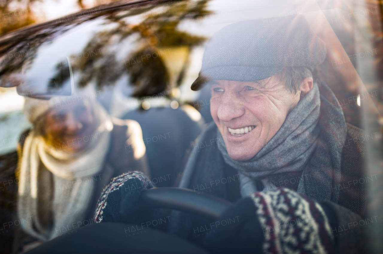 Beautiful senior woman and man in winter clothes driving a car