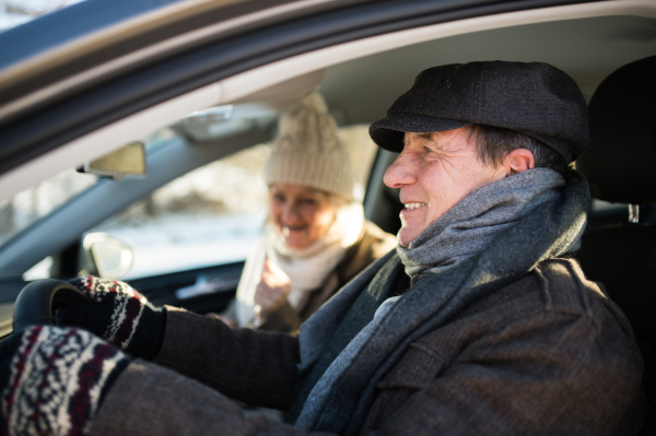 Beautiful senior woman and man in winter clothes driving a car