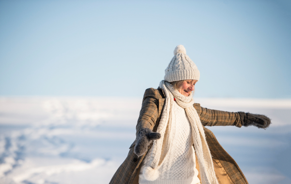 Beautiful senior woman on a walk in sunny winter nature, enjoying herself.