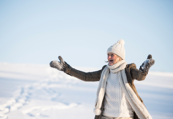 Beautiful senior woman on a walk in sunny winter nature, having fun.