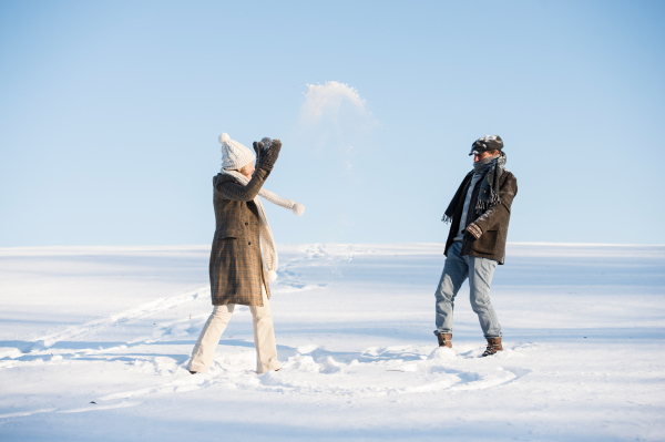 Beautiful senior woman and man on a walk in sunny winter nature, having fun.