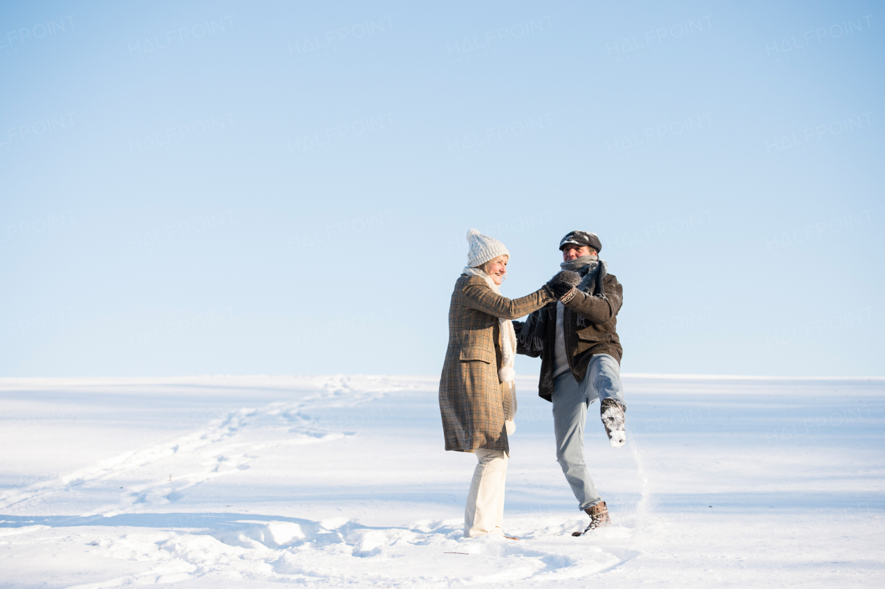 Beautiful senior woman and man on a walk in sunny winter nature, having fun.