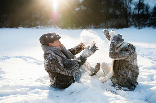 Beautiful senior woman and man on a walk in sunny winter nature, enjoying snow and having fun.