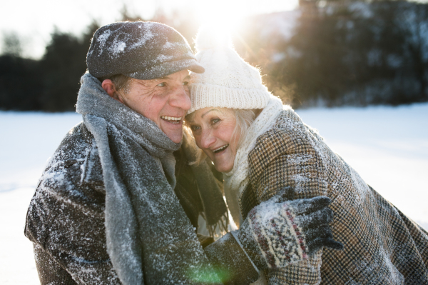 Beautiful senior woman and man on a walk in sunny winter nature, having fun.