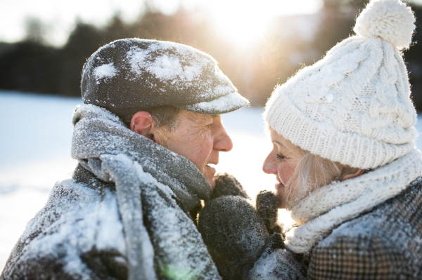 Beautiful senior woman and man on a walk in sunny winter nature, having fun.