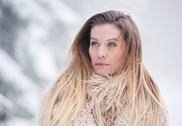 Beautiful young blonde woman in fur coat on a walk in winter nature. Snowy day.