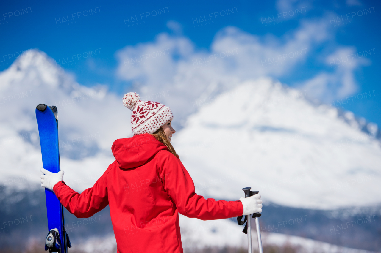 Young woman skiing outside in sunny winter mountains