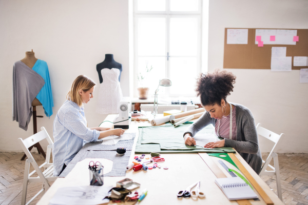 Young creative women with sewing machine working in a studio, startup business.