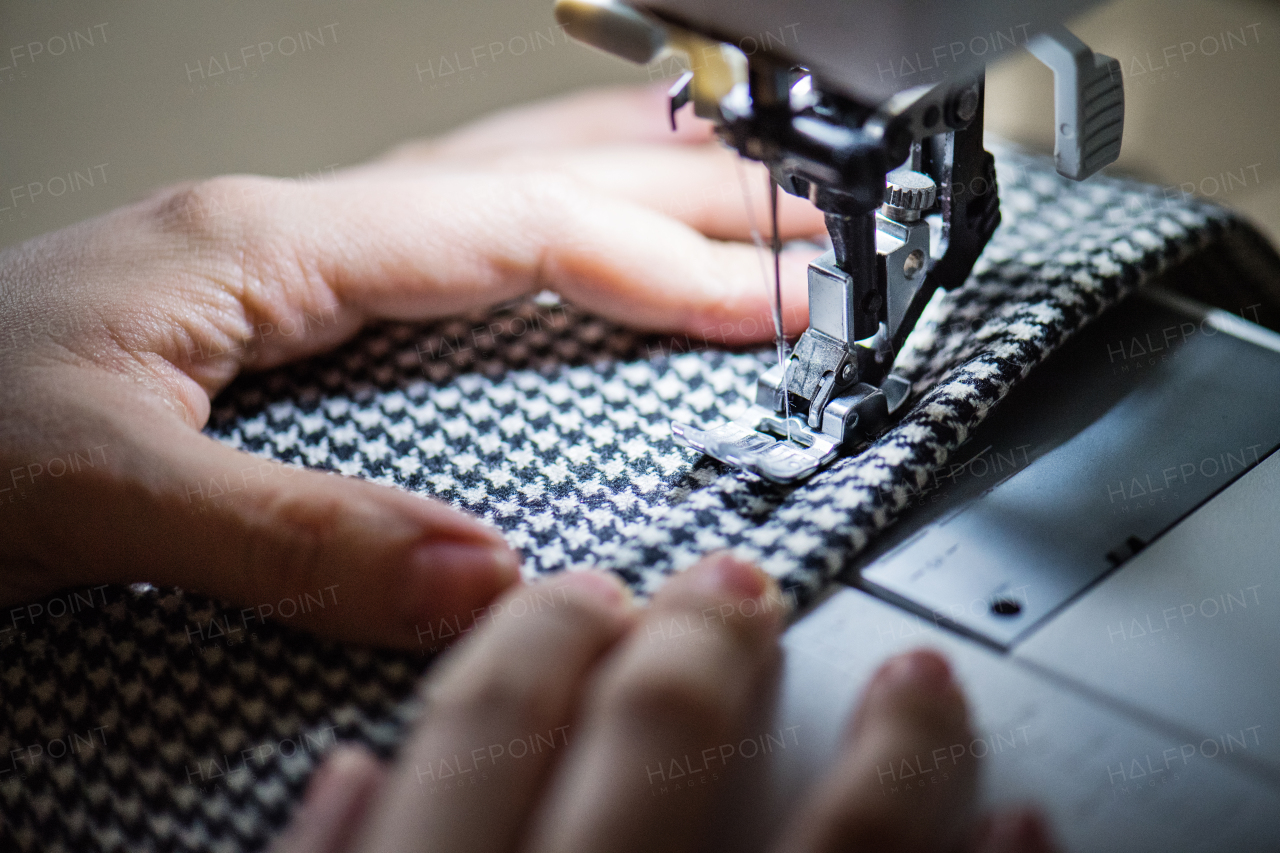 Unrecognizable young creative woman using sewing machine, startup business. Close up.