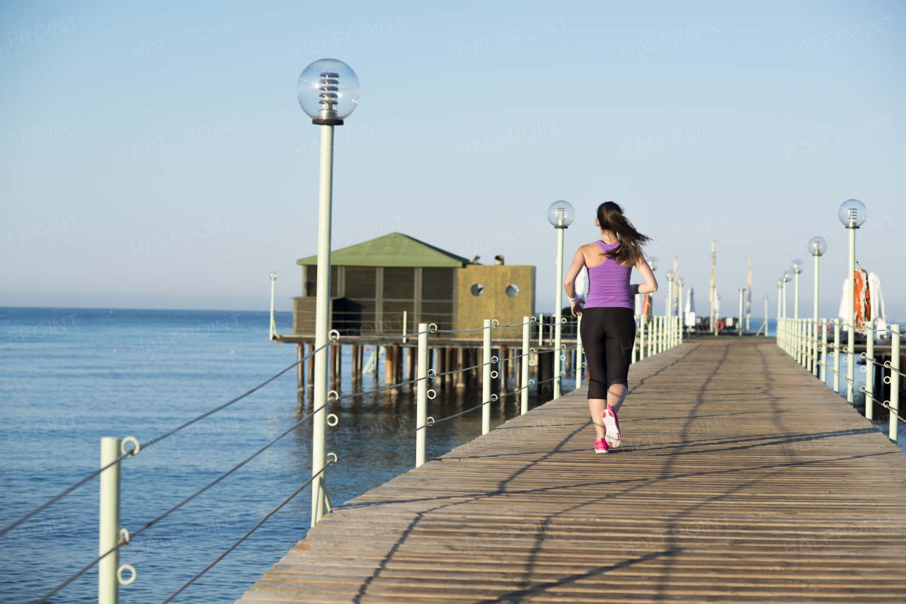 Young beautiful woman running along the shore.