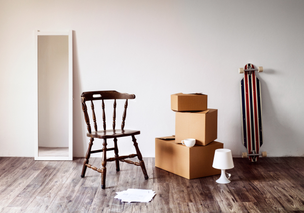 Packed cardboard boxes, mirror, chair and other stuff in empty house. Moving in a new home concept.