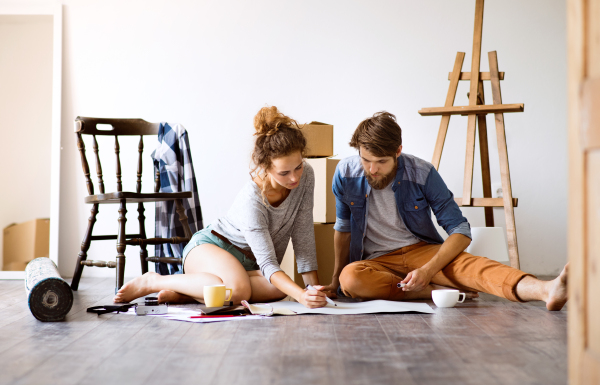 Young married couple moving in a new house, unpacking things, resting and making plans.