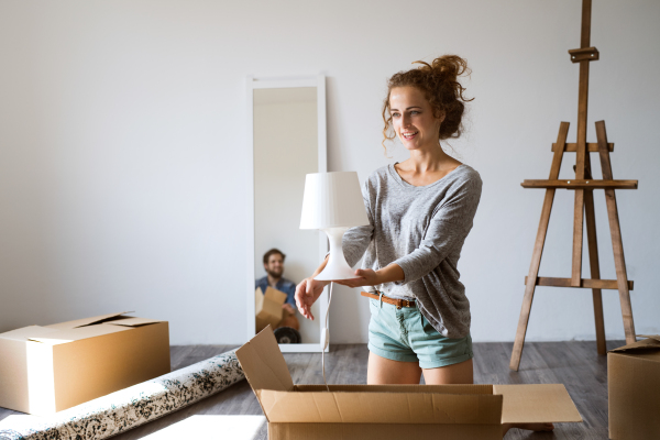 Young married couple moving in new house, unpacking boxes.