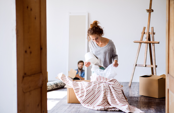 Young married couple moving in new house, unpacking boxes.