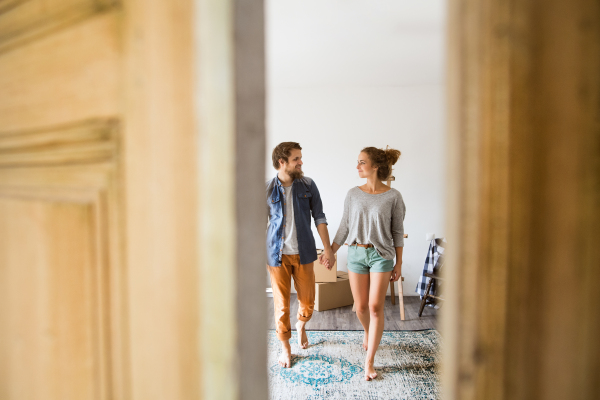 Young married couple moving in a new house, entering through the door.