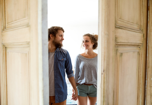 Young married couple moving in a new house, entering through the door.