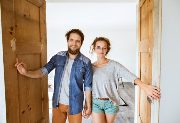 Young married couple moving in a new house, entering through the door.