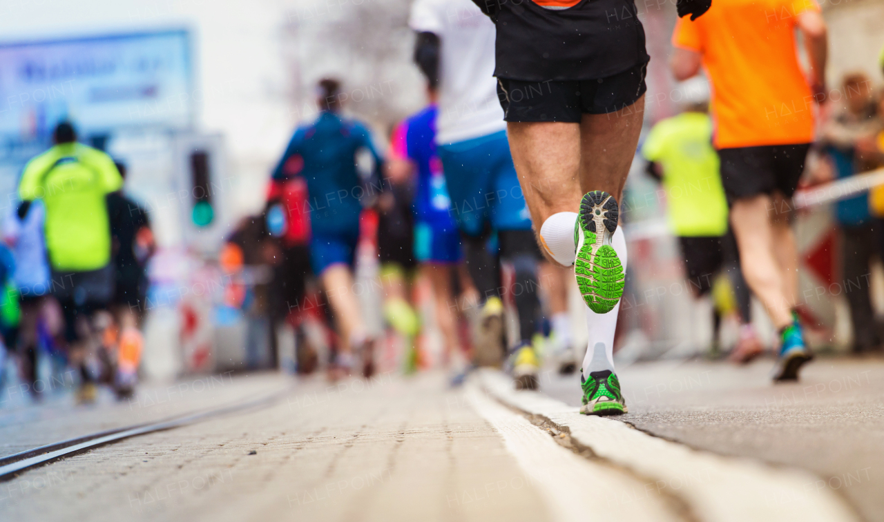 Young active runner during the marathon, in the city.