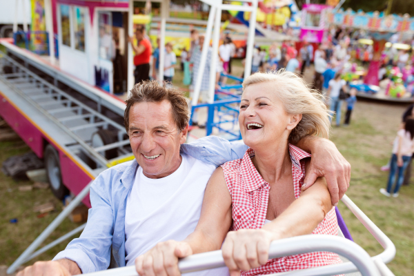 Senior couple having fun on a ride in amusement park. Summer vacation.